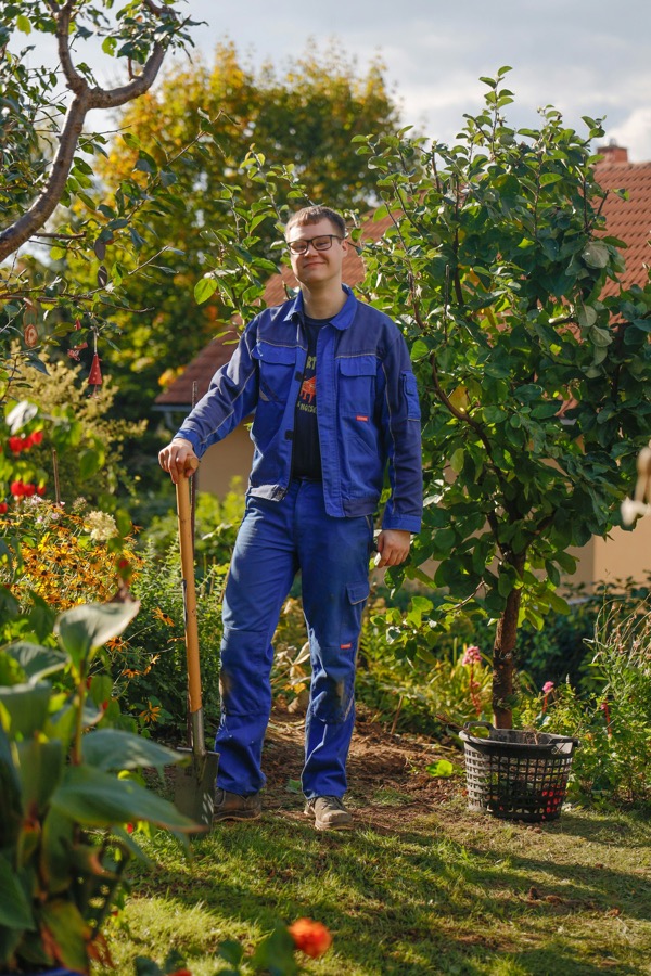 A garden crew member with a spade in a raised-bed garden